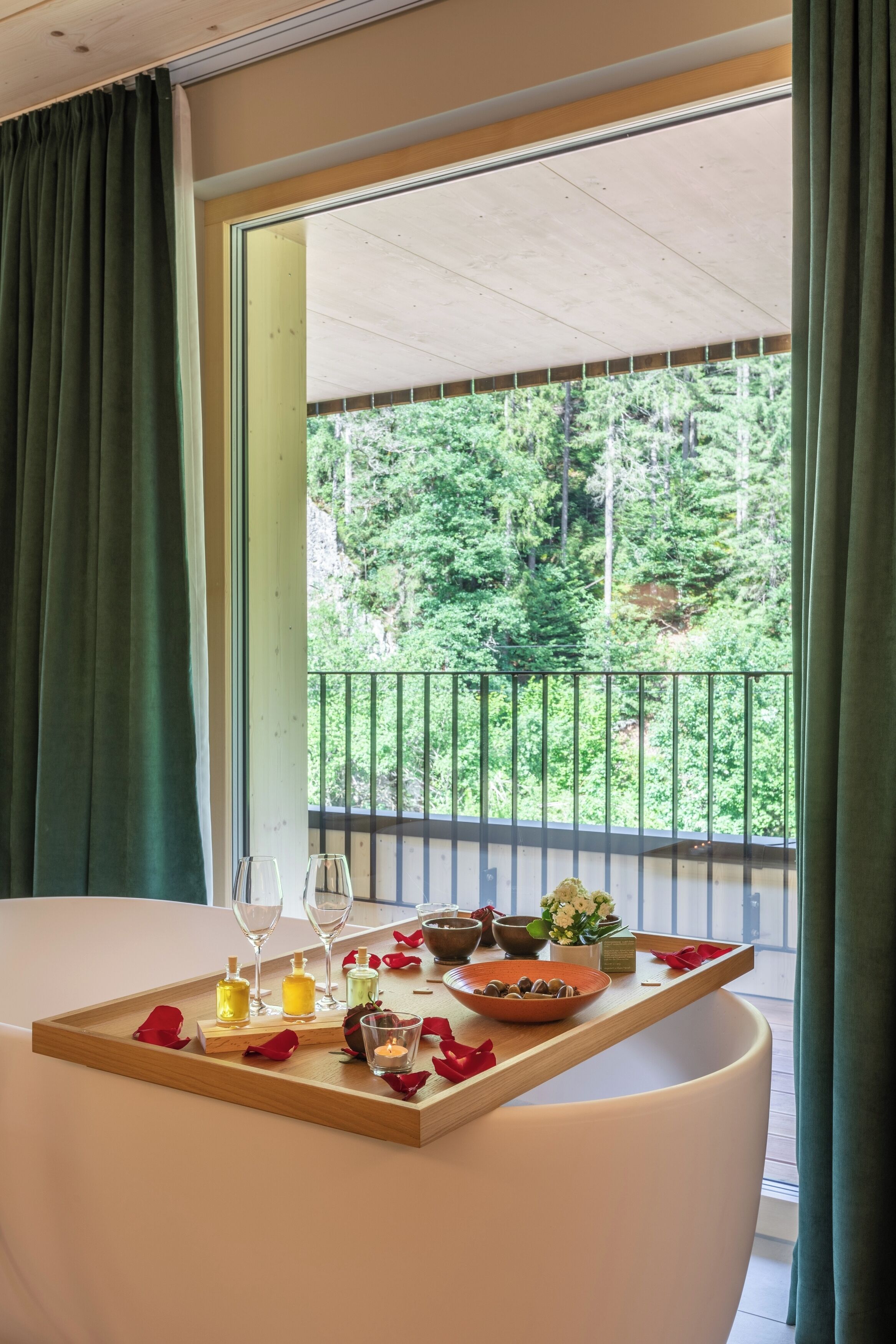 A dining table with a tray, candles, and a view of a balcony with greenery.