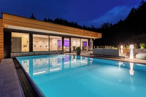 A modern building with a swimming pool, large windows, and outdoor seating. - Sackmann Design Genuss & SPA Resort (Baiersbronn)