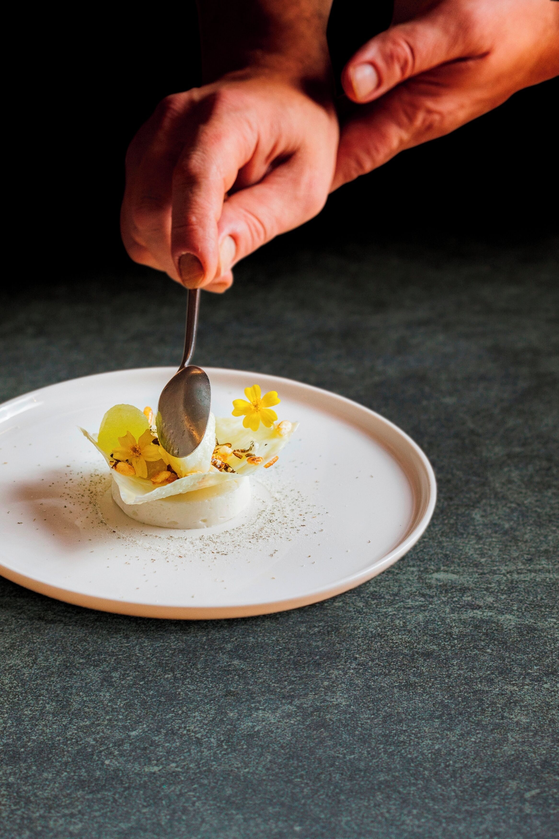 A person using a spoon to serve a dessert on a white plate.