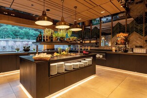 Una cocina moderna con una isla central, luces colgantes y vistas a la vegetación.