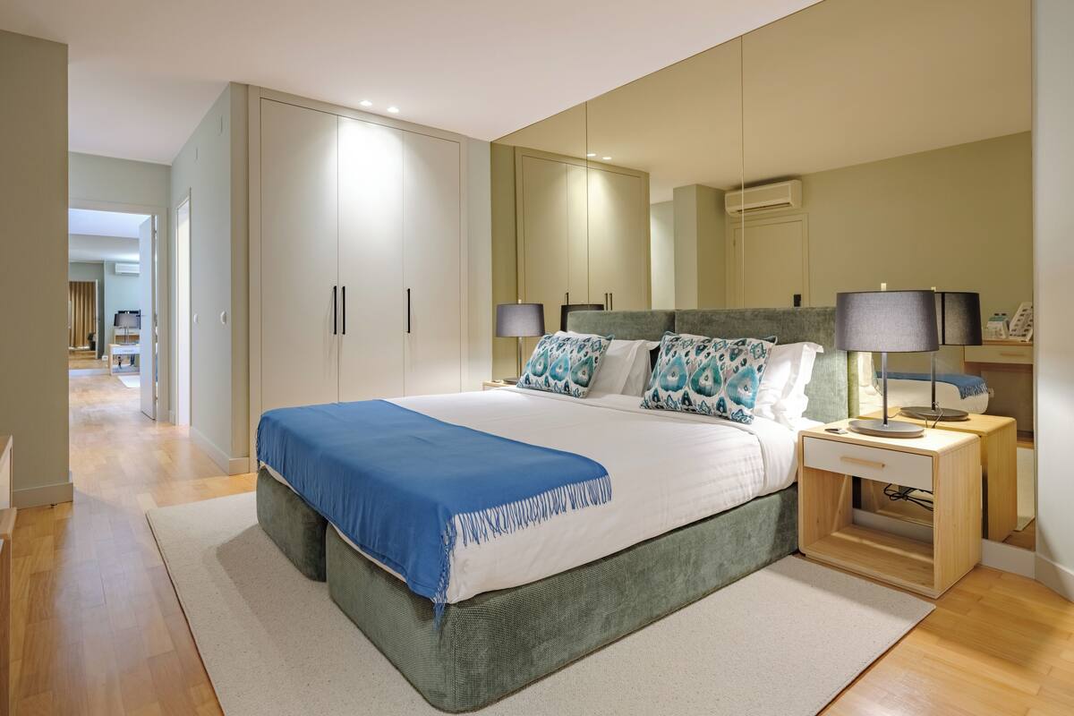 Un dormitorio moderno con una cama grande, una mesita de noche, un espejo y un armario.