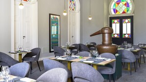 En restaurang med runda bord, grå stolar och en stor träfat.