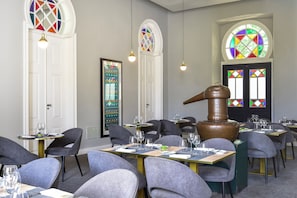 Restaurante com mesas redondas, cadeiras cinzentas e um grande barril de madeira.