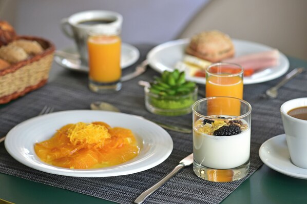 A breakfast setting with plates of food, glasses of orange juice, and a cup of coffee. - Caldas Monchique Villa Termal Spa Resort (Monchique)