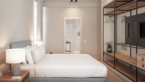 Ett modernt hotellrum med en säng, en sänglampa, en tv och en garderob med en spegel.