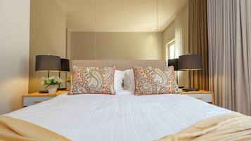 A hotel room with a large bed, two nightstands, two lamps, and a window with curtains.