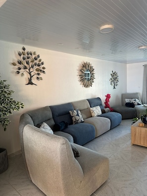 A modern living room with a sectional sofa, decorative wall art, and a potted plant.