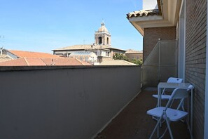 Uma varanda com vista para um campanário e telhados de cerâmica.