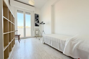 Een kamer met een bed, een houten plankunit, een statief en een radiator.