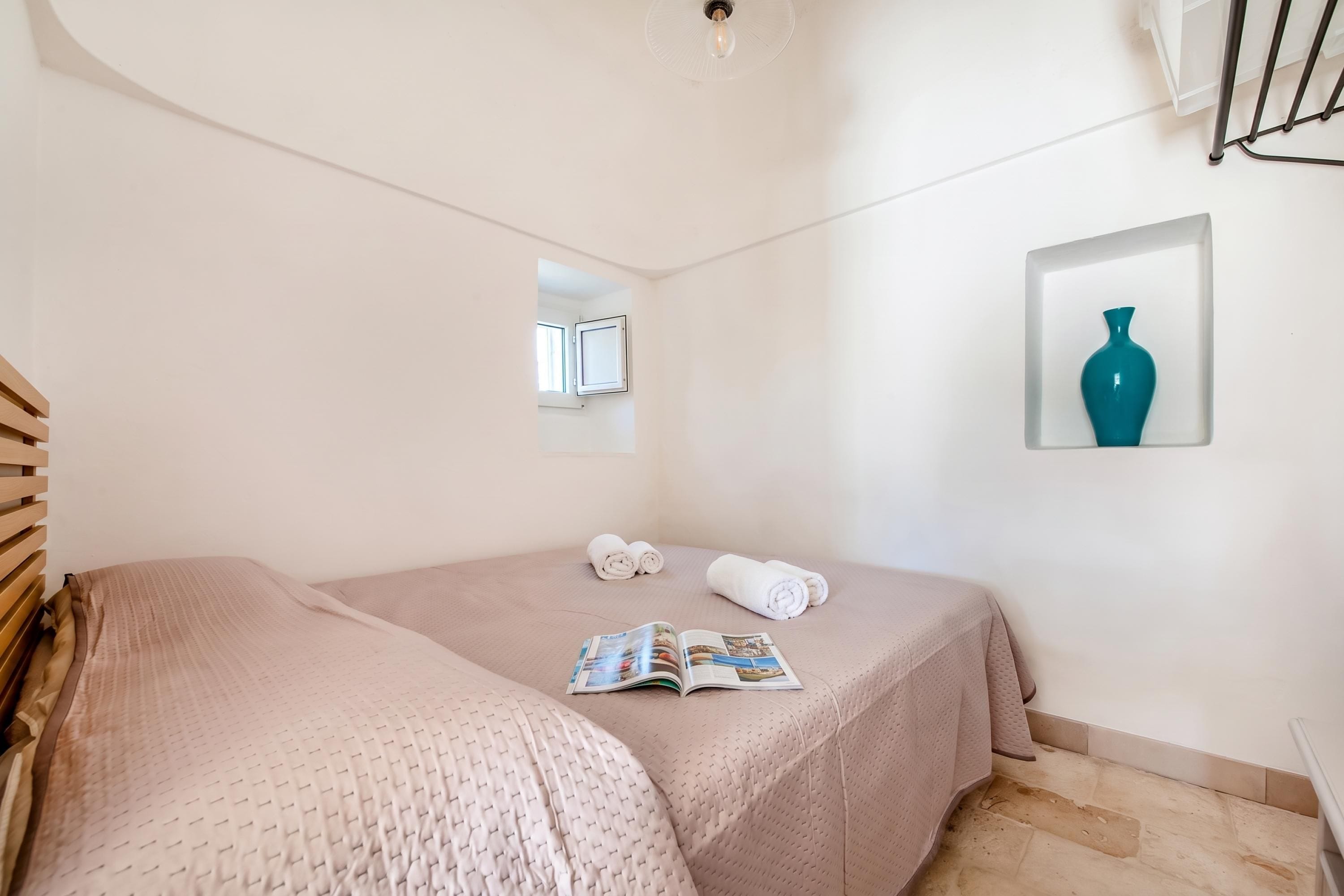A bedroom with a bed, a window, a framed picture, and a magazine on the bed.