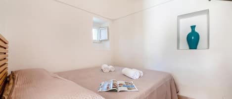 A bedroom with a bed, a window, a framed picture, and a magazine on the bed.