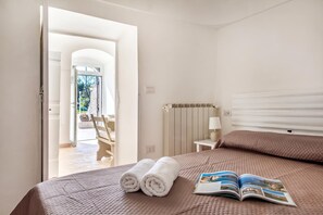 A hotel room with a bed, a book, and a view of the outside. - Trulli Trullo in Locorotondo (Locorotondo)