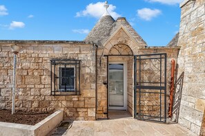 A stone building with a door, a window, and a metal gate.