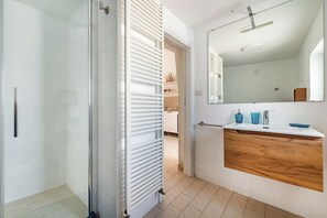A modern bathroom with a shower, a vanity with a mirror, and a wooden countertop.