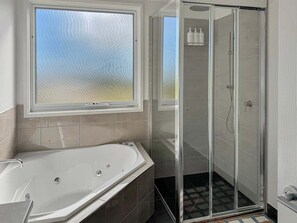 Un bagno con vasca, cabina doccia in vetro e finestra.