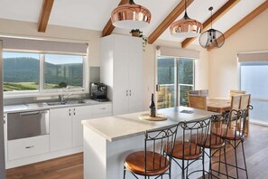 Una cucina moderna con mobili bianchi, un'isola centrale e un'area pranzo con sedie in metallo.