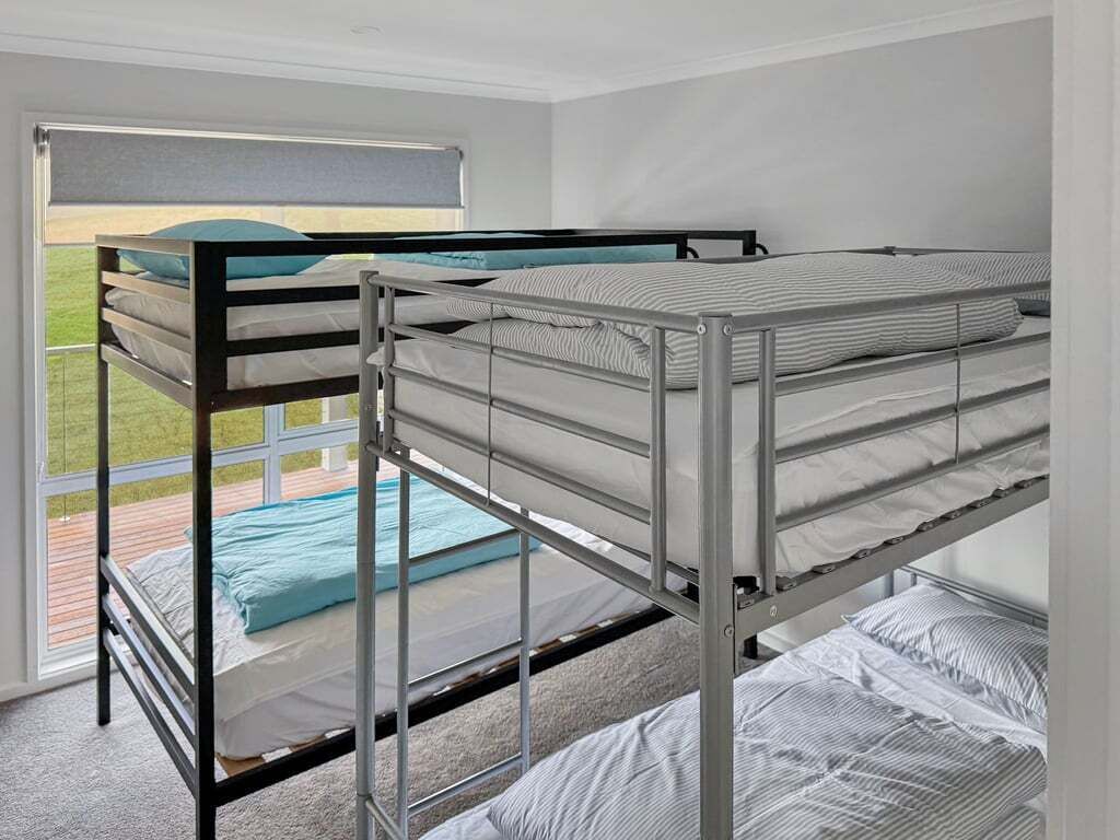 A bunk bed room with a view of a wooden deck and a window.