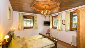 A bedroom with two beds, a TV, a wooden wardrobe, and a chandelier. - Ferienhaus Höllbacher by we rent (Bad Gastein)