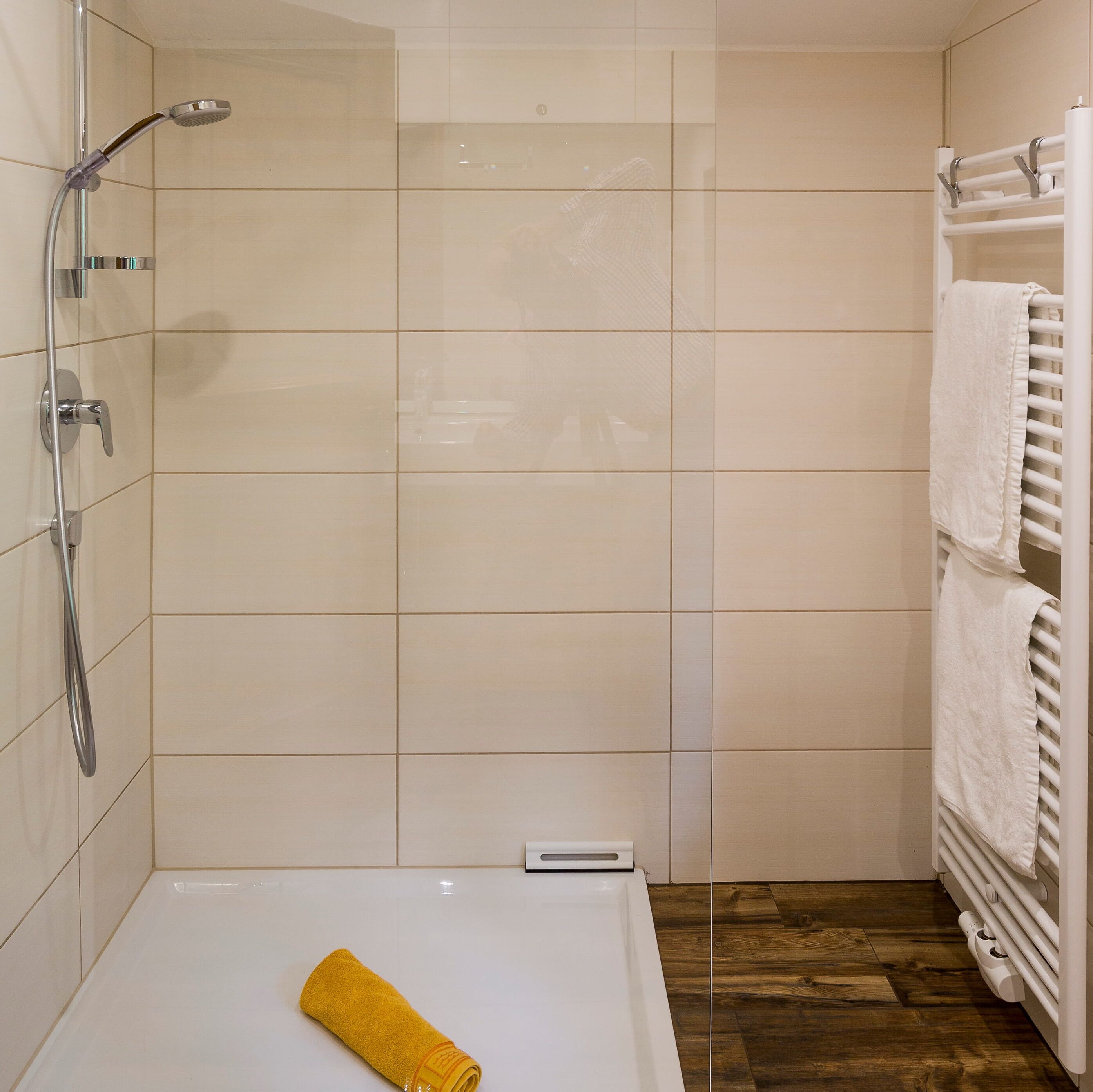 A bathroom with a shower, a bathtub, and a towel rack.
