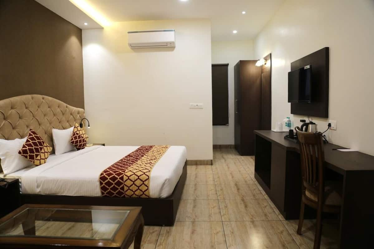 Habitación de hotel con cama, escritorio, televisión y minibar.