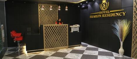 A reception area with a checkered floor, a reception desk, a red chair, and a decorative vase.