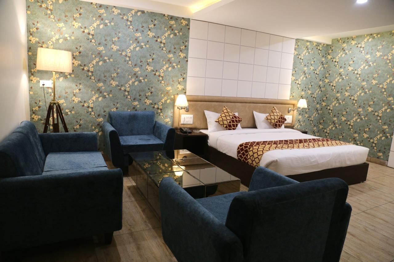 A hotel room with a bed, two armchairs, a small table, and a floor lamp.