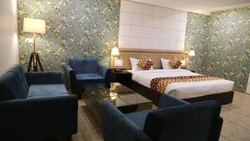 A hotel room with a bed, two armchairs, a small table, and a floor lamp.