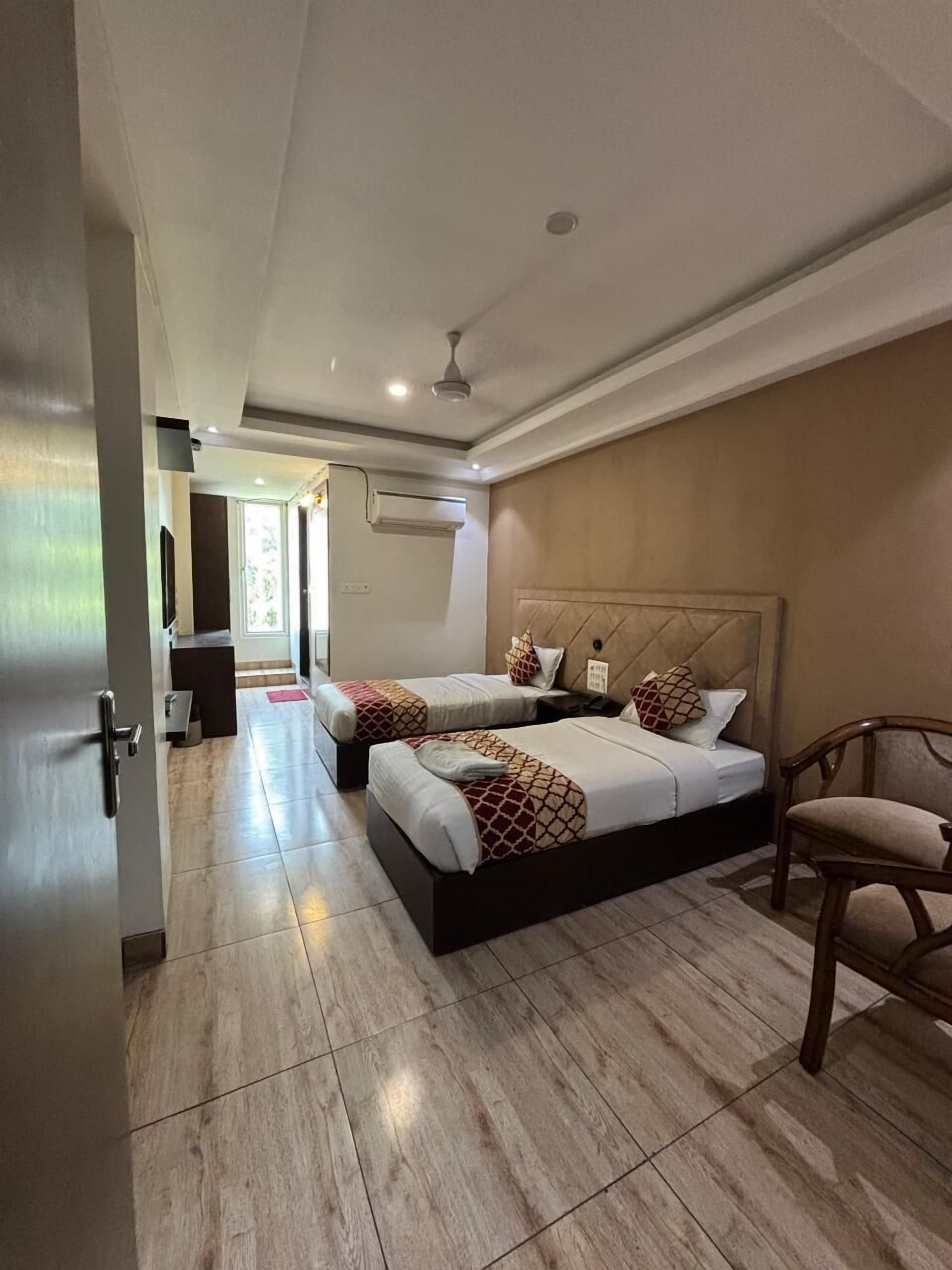 Une chambre d’hôtel avec deux lits, une chaise, un ventilateur de plafond et un appareil de climatisation.