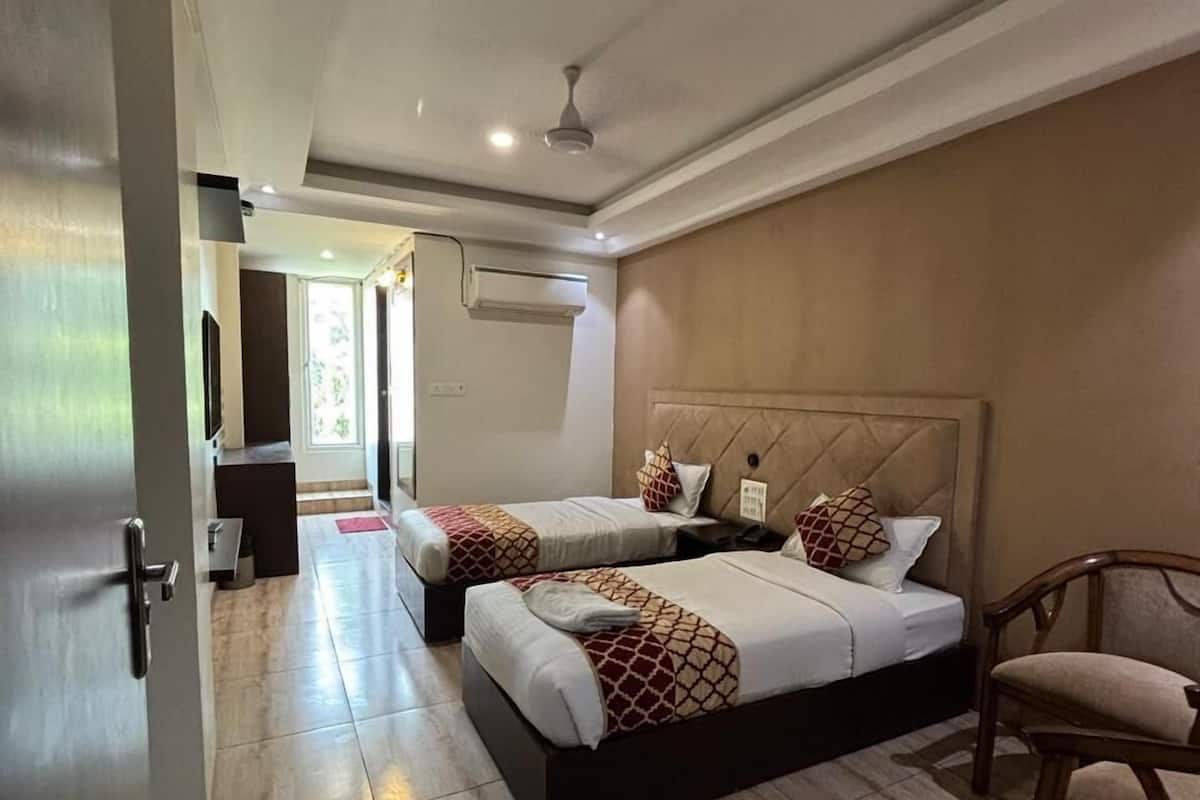Habitación de hotel con dos camas, una silla, ventilador de techo y aire acondicionado.