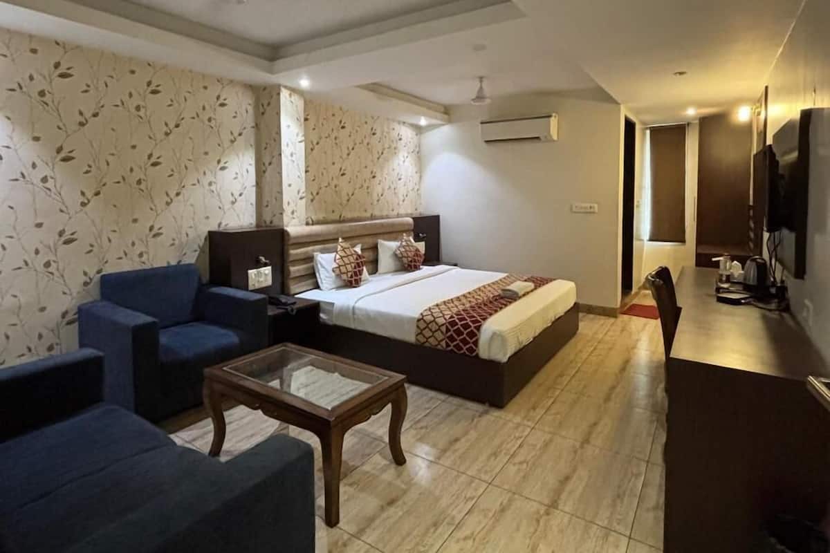 Una habitación de hotel con cama, sofá, mesa de centro y televisión.