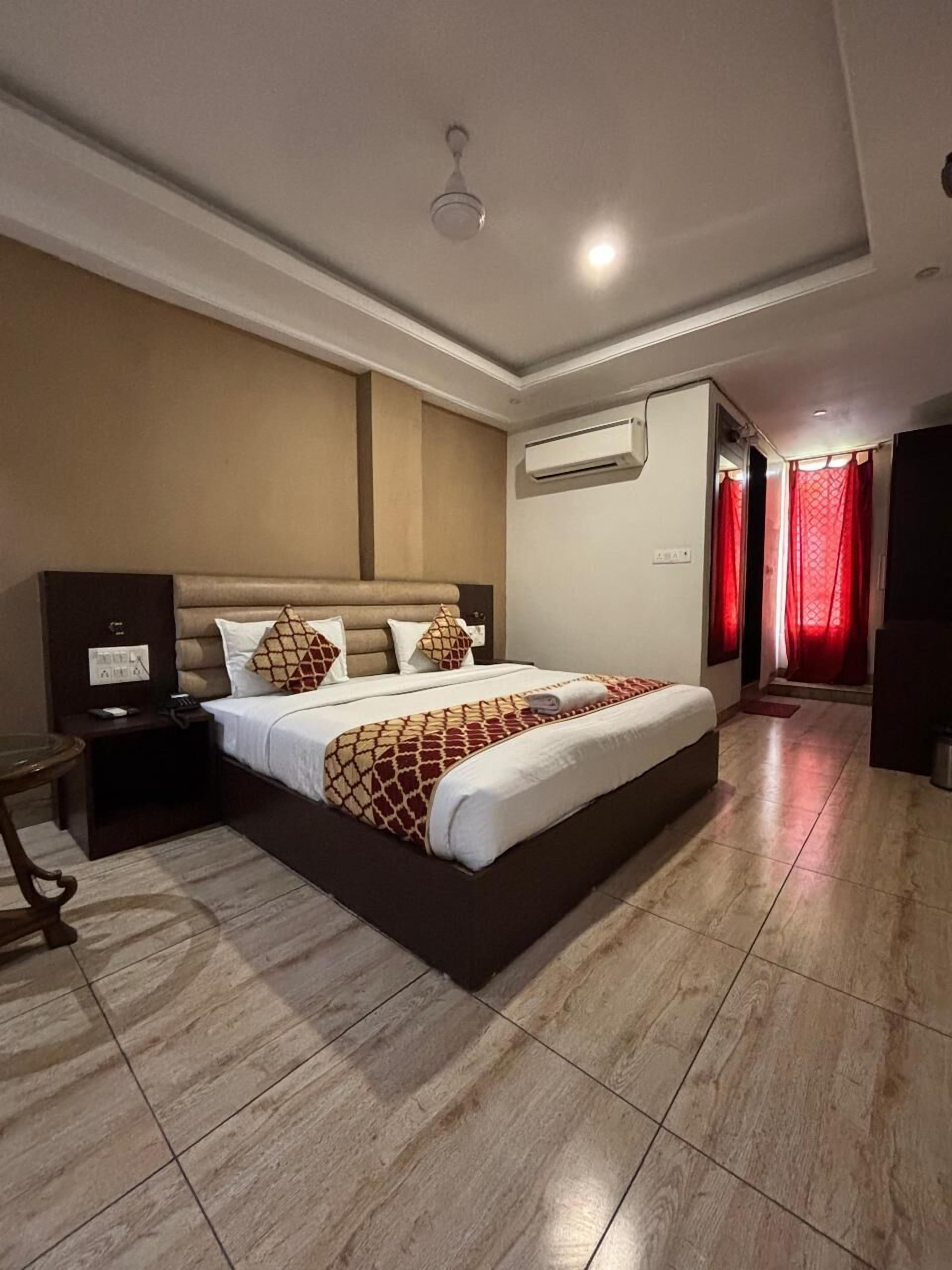 Une chambre d’hôtel avec un grand lit, un appareil de climatisation, une table de chevet et une petite table.