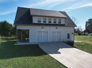 A two-story house with a garage, a covered porch, and a concrete driveway.