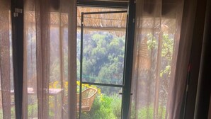 Ein Zimmer mit einem Bett, einem Tisch und einem Stuhl vor einer Glastür.