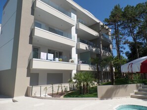 A multi-story building with balconies, a swimming pool, and a red and white tent. - Nice Flat for Five Guests in a Modern Residence (San Michele al Tagliamento)