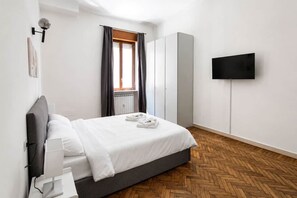 Una camera da letto con un letto, una televisione a parete e una finestra con tende.