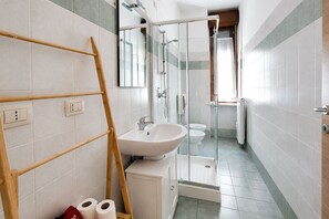 Een badkamer met douche, toilet en wastafel.