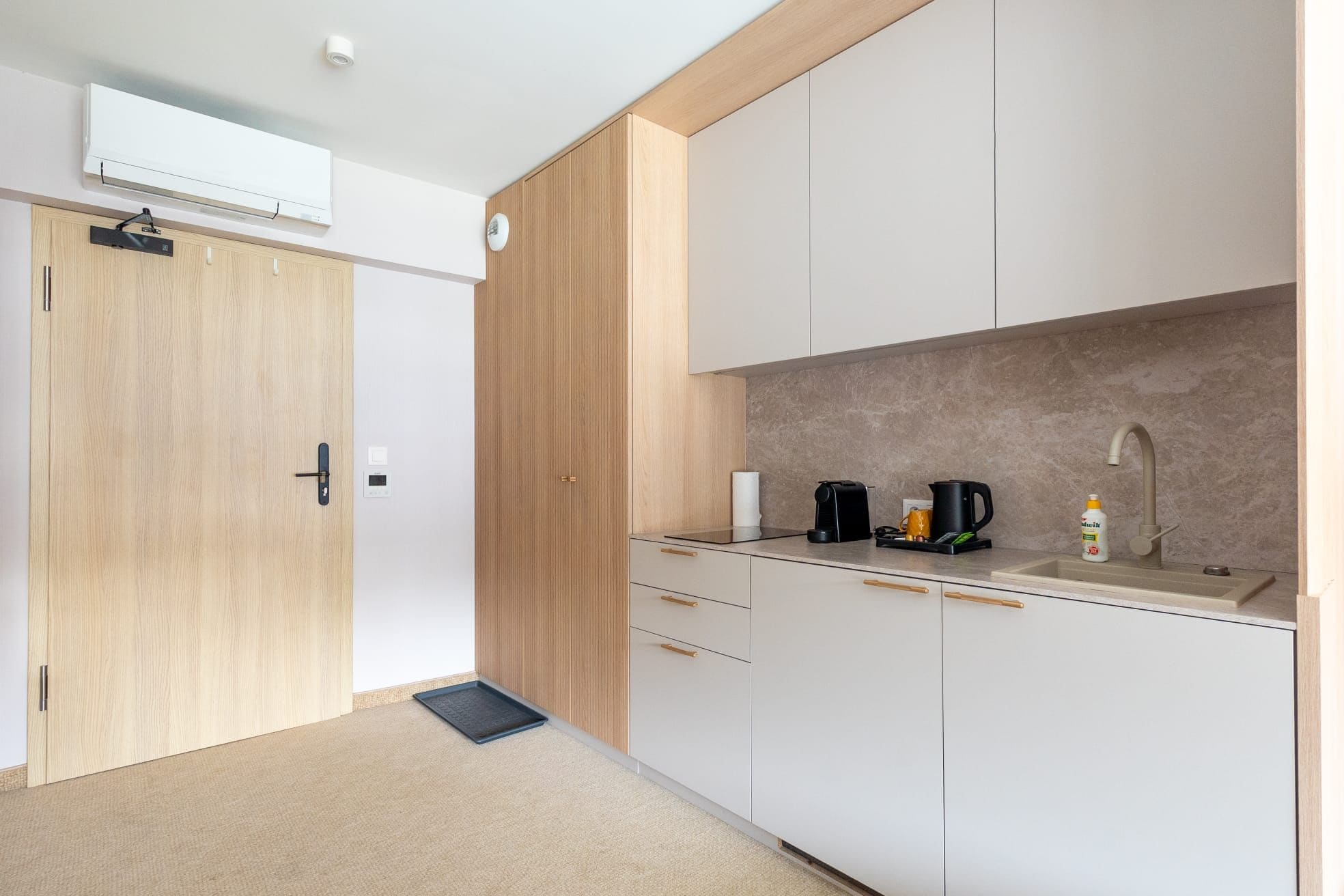 A modern kitchen with a built-in oven, a coffee maker, and a sink.