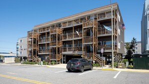 A multi-story building with a wooden facade, a car in the foreground, and a clear blue sky. - Immaculant One Bedroom Condo, Conveniently Located On 40th ST (Ocean City)
