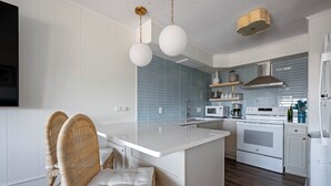 A modern kitchen with white cabinetry, a central island, a built-in oven, and a microwave. - Immaculant One Bedroom Condo, Conveniently Located On 40th ST (Ocean City)