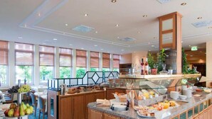 A hotel breakfast area with a buffet, wooden cabinets, and large windows. - 4 Person Holiday Park Home in Neu-isenburg (Neu-Isenburg)