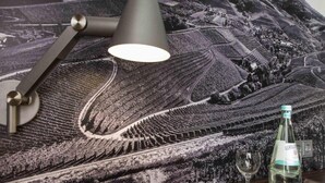 A table with a lamp, a bottle, and a glass on a tablecloth with a landscape design. - 4 Person Holiday Park Home in Offenburg (Offenburg)