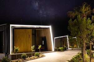 Un edificio moderno con grandes puertas de vidrio, interior de madera y exterior bien iluminado.