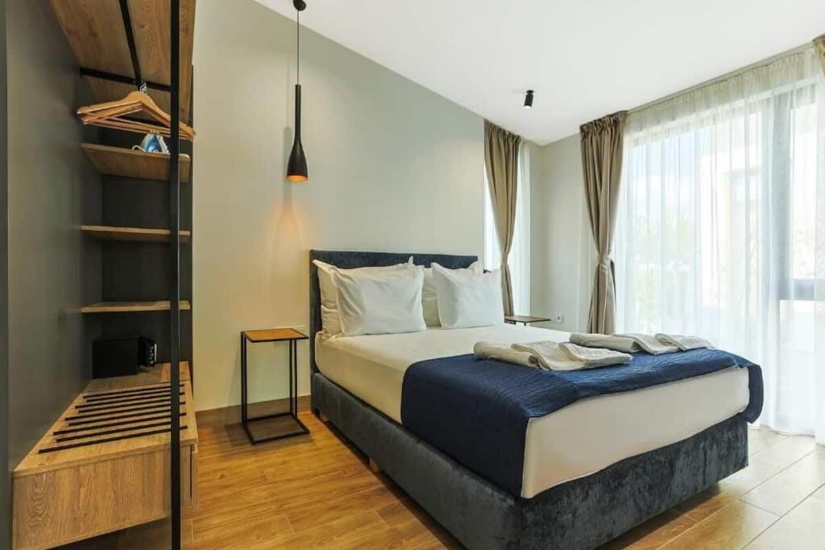 Un dormitorio con cama, mesita de noche, lámpara colgante y estante empotrado.