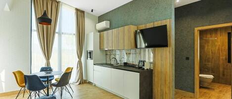 A modern kitchen with a flat-screen TV, a dining area with a table and chairs, and a living room with a sofa and a coffee table.