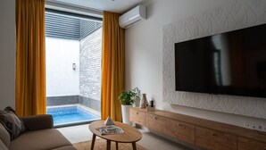 A modern living room with a flat-screen TV, a sofa, a coffee table, a small pool, and a sliding glass door. - IGMAR Villas & Aparts  (Tashkent)