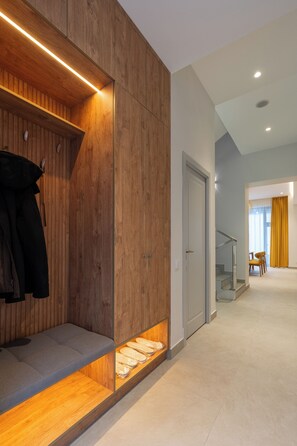 Un interior moderno con un banco de madera, un perchero y una escalera que lleva a otra habitación.