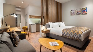 A modern hotel room with a bed, a desk, a chair, a small table, and a sofa. - IGMAR Villas & Aparts  (Tashkent)