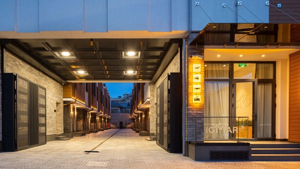 A hotel corridor with a brick wall, a glass door entrance, and a staircase leading to the upper floor. - IGMAR Villas & Aparts  (Tashkent)