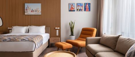 Ein Hotelzimmer mit einem Bett, einer Couch, zwei Beistelltischen, einer Topfpflanze und Bildern an der Wand.