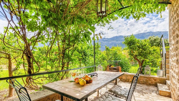 An outdoor patio with a table set for two, surrounded by stone walls and greenery. - Holiday Home 'Ca N'Antonia' citrus farm stay (Sóller)